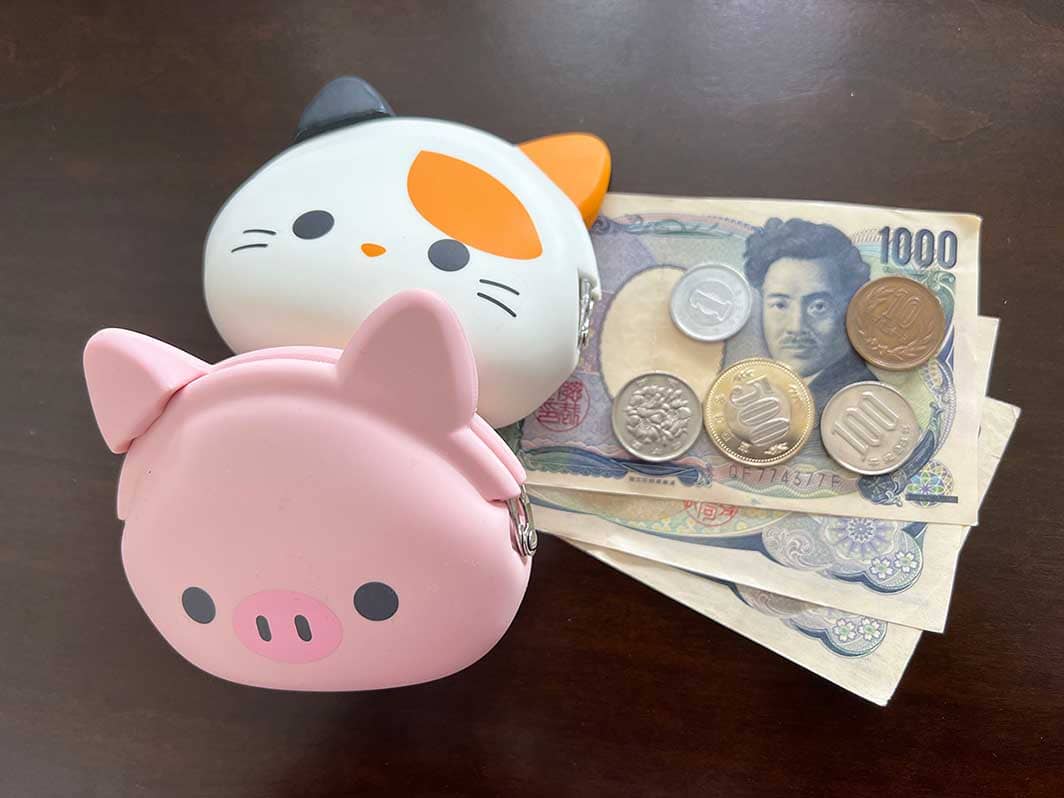 Japanese bills and coins next to colorful cute and compact snap-on coin holders or coin purses with shape of animal faces